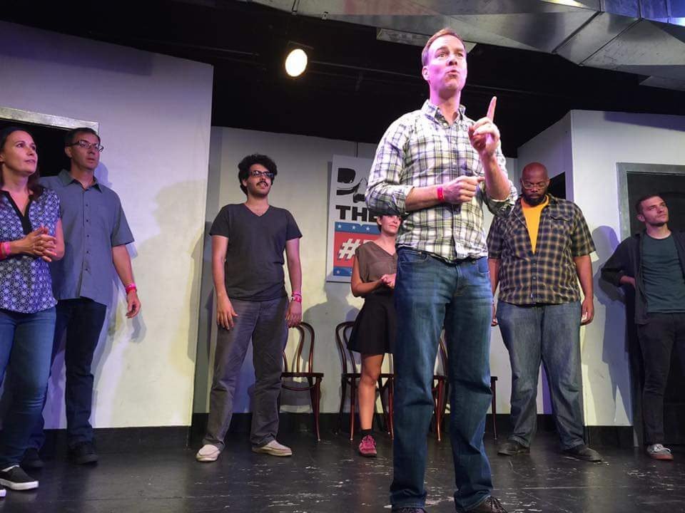 Patrick McInnis leading a live improv scene with his ensemble